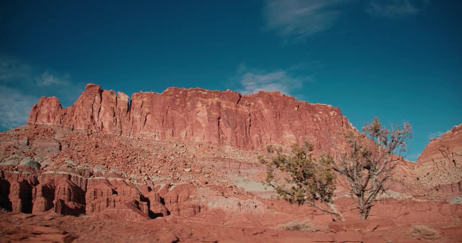A red rock formation is shown in a desert on a sunny day