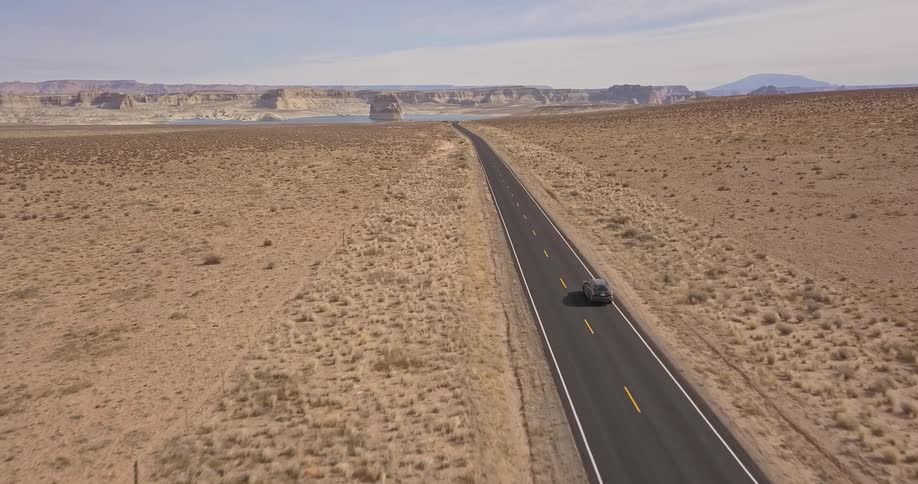A vehicle travels down a desert road