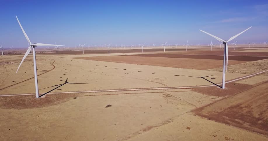 Wind turbines rotate in desert landscape on a sunny day