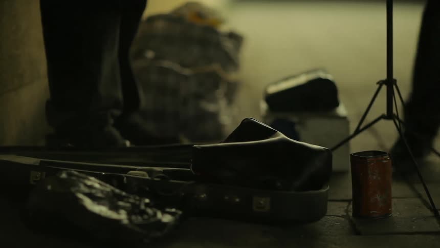 A person drops change into a street artist's can