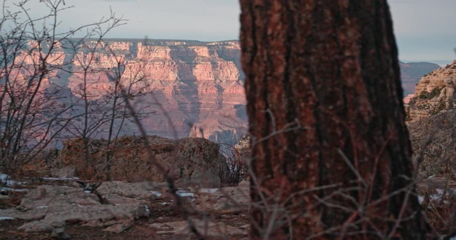 Snow dots the landscape of a desert canyon at dawn