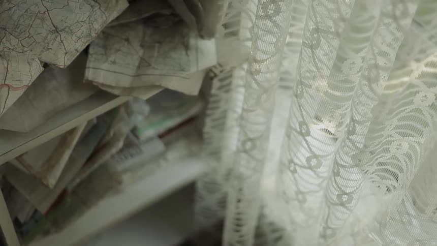 A curtains hangs down next to a bookshelf