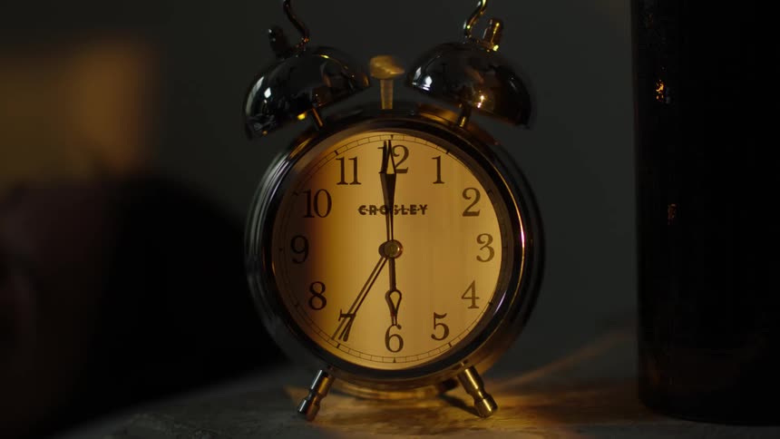 An alarm clock is ticking and ringing at dawn
