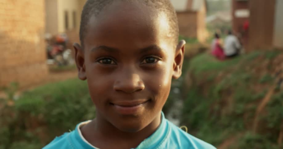 A child stands outside smiling in the sunshine