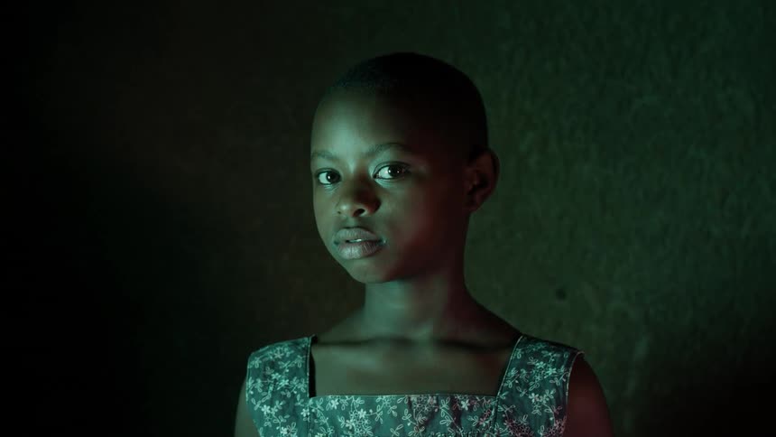 A young girl stares in a dark room