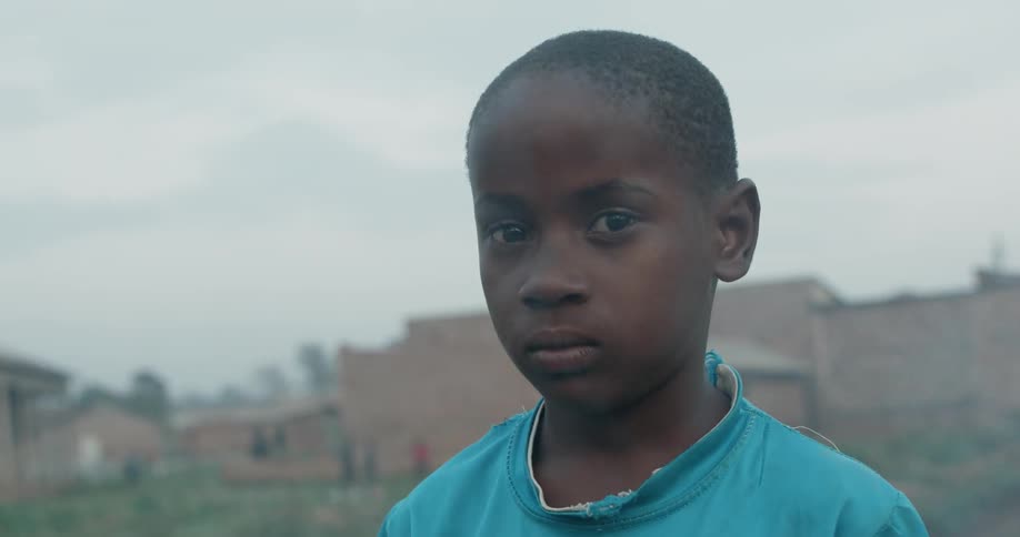 A young boy stands outside as smoke passes by