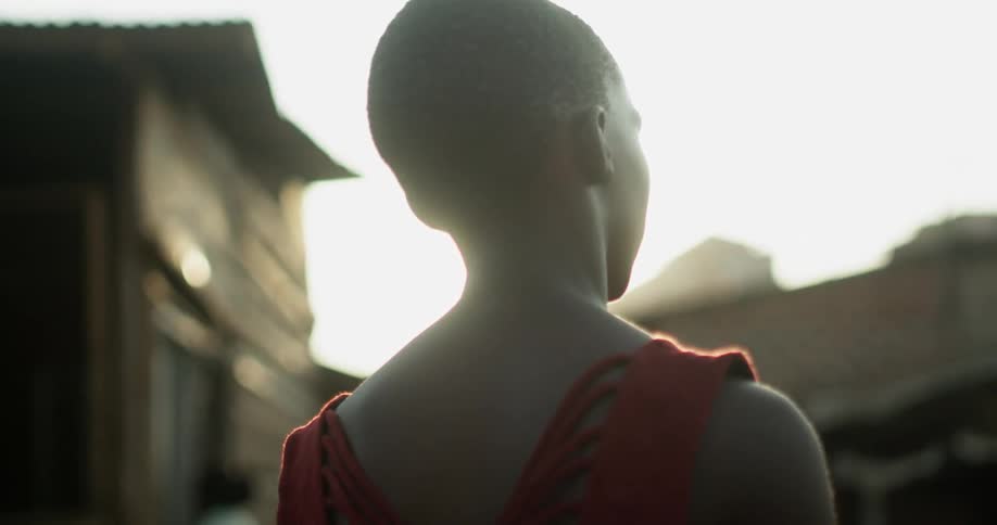 A woman stands outside under the sun