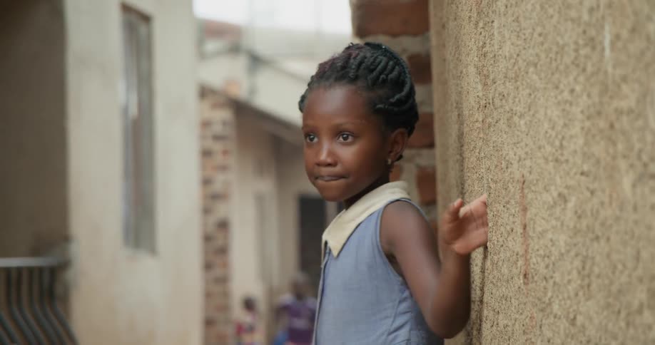 Young girl stands outside next to a building