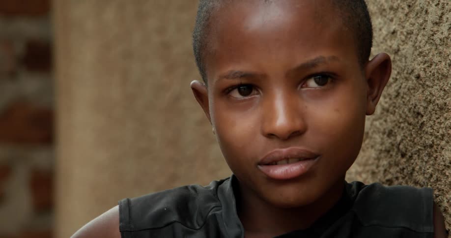 An african boy is leaning on a wall and smiling