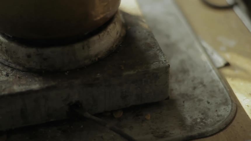 The base of a clay pot on an old stone pedestal with flickering shadows