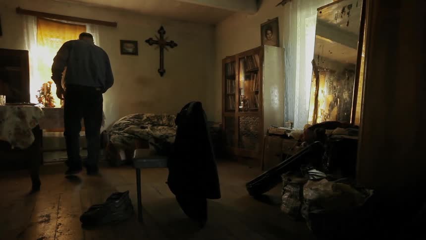 A man kneels at a statue and prays inside his house