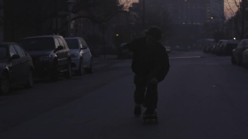A boy rides a skateboard down a city street