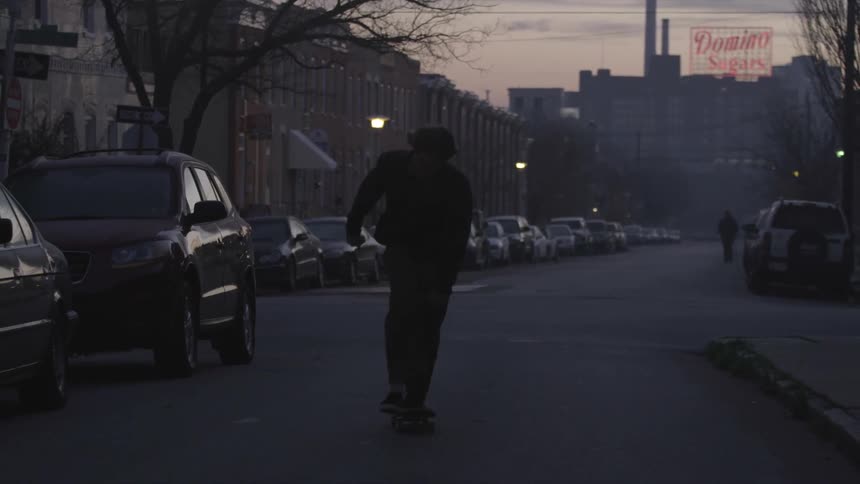 Person riding skateboard on city street at dusk