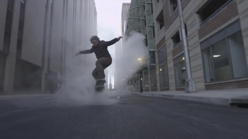 A man skateboarding through steam on a city street