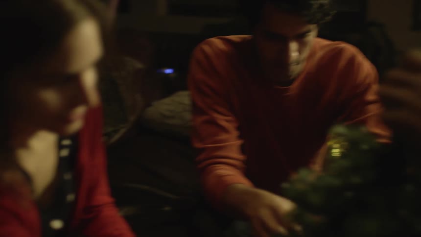 People decorate a small christmas tree