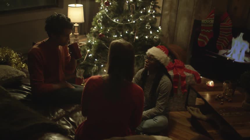 Three friends sit around a living room during the christmas holiday