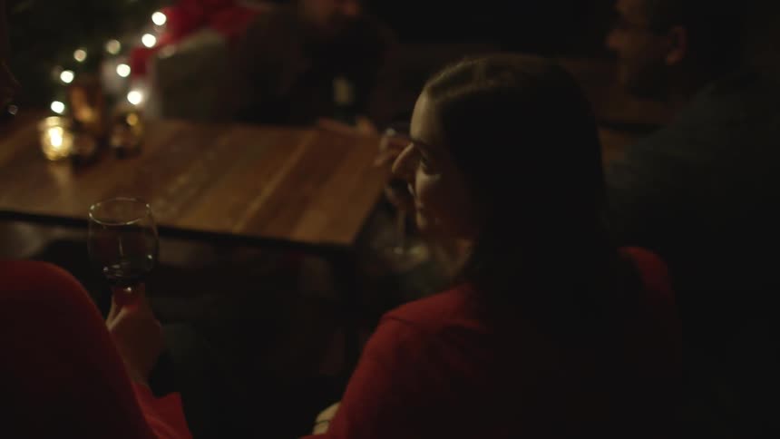 People drink wine in front of an illuminated christmas tree