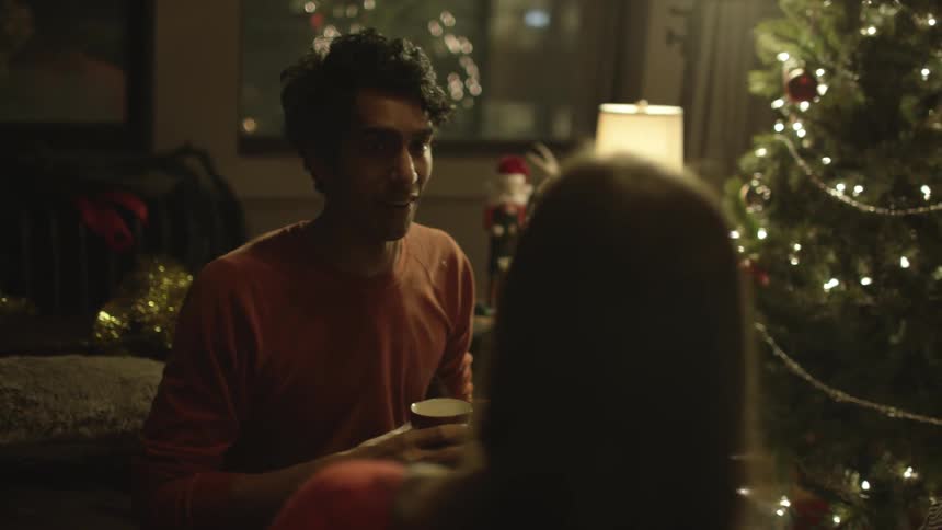A man talks to friends near a christmas tree