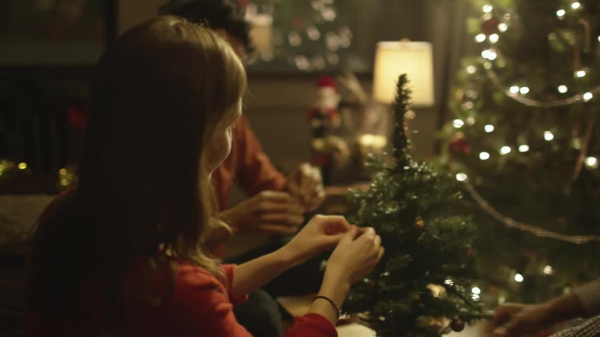 A group of people decorate a miniature christmas tree