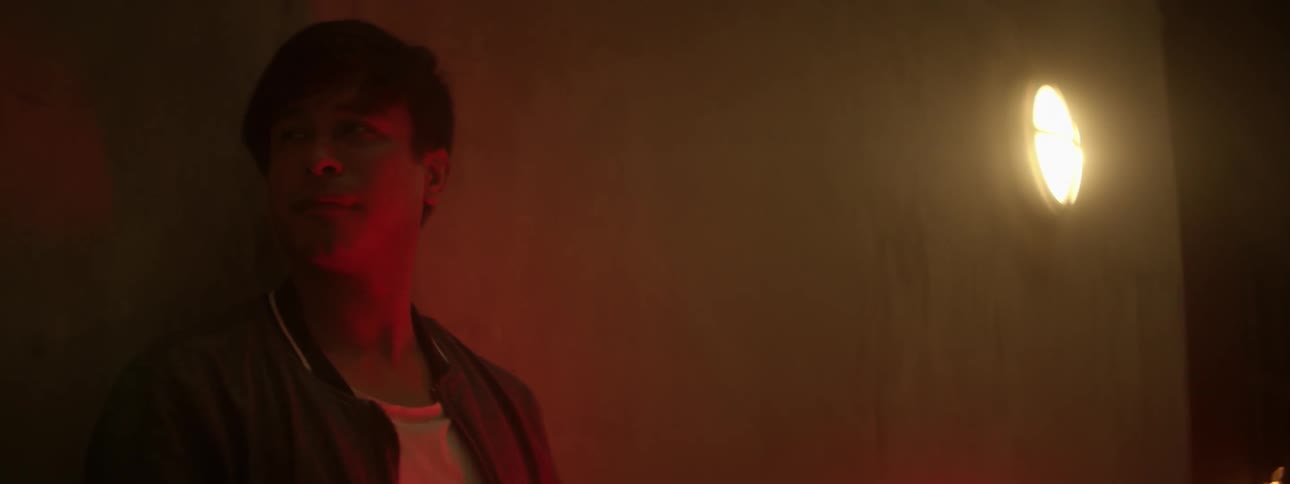 A boy holding a light leans against a wall