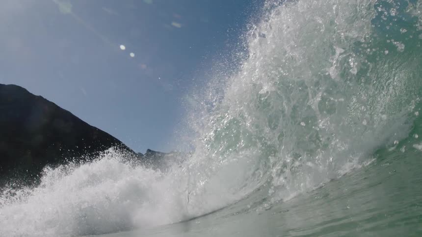 A wave crests and crashes as it rolls toward the shore