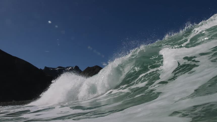 A wave crests and crashes as it rolls toward the shore
