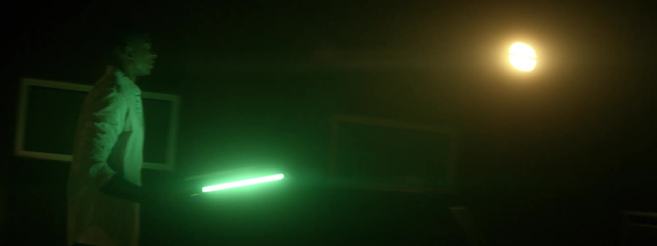 A man walks outside with a bright flashlight at night