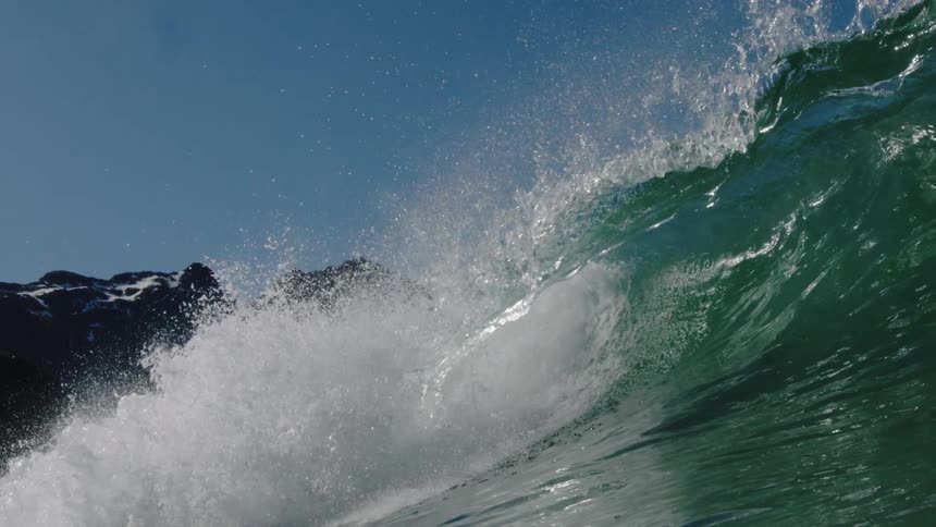 A wave crests and crashes as it rolls toward the shore