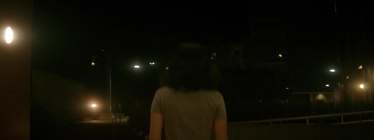 A woman carries an orange flashlight outside at night
