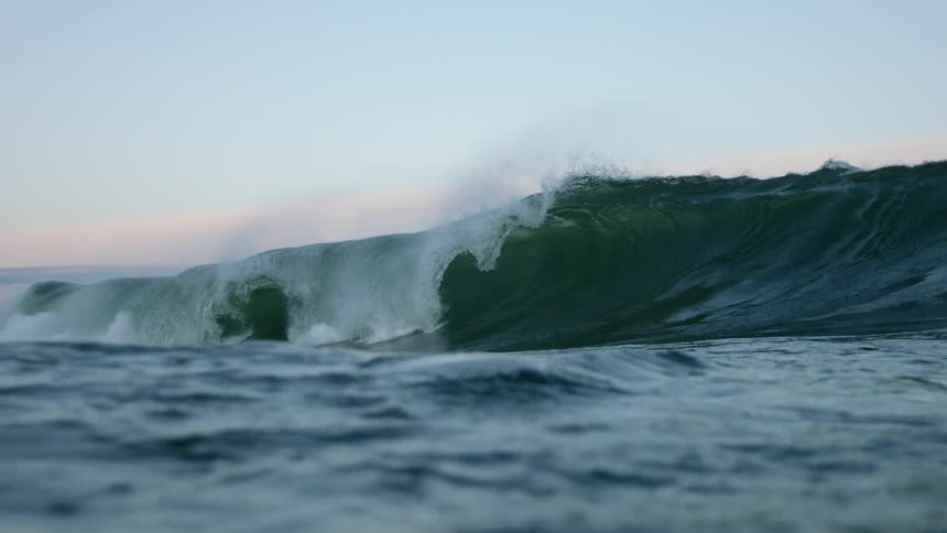 A tall wave crests and crashes back into the ocean
