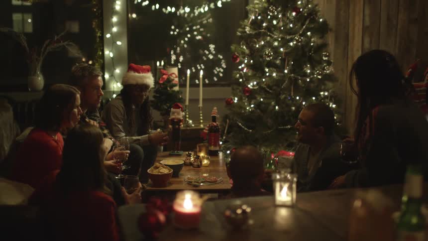 People sitting at a table talking with christmas decorations all over