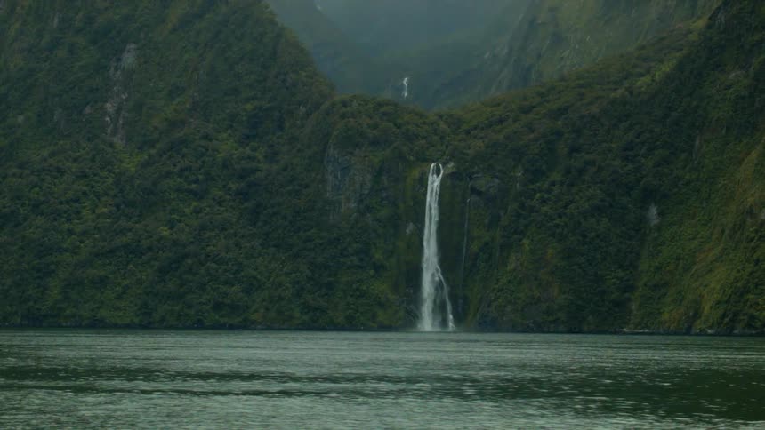 A waterfall gushes into a mountain lake