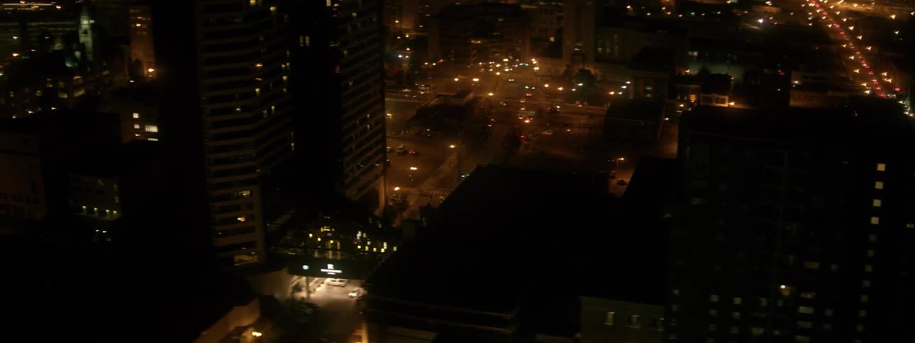 Cars drive down a city street at night