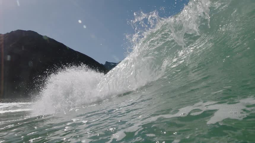 A tall wave crests as it approaches the shore