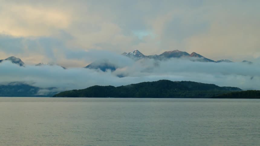 Clouds hover over hills near the coast at dawn