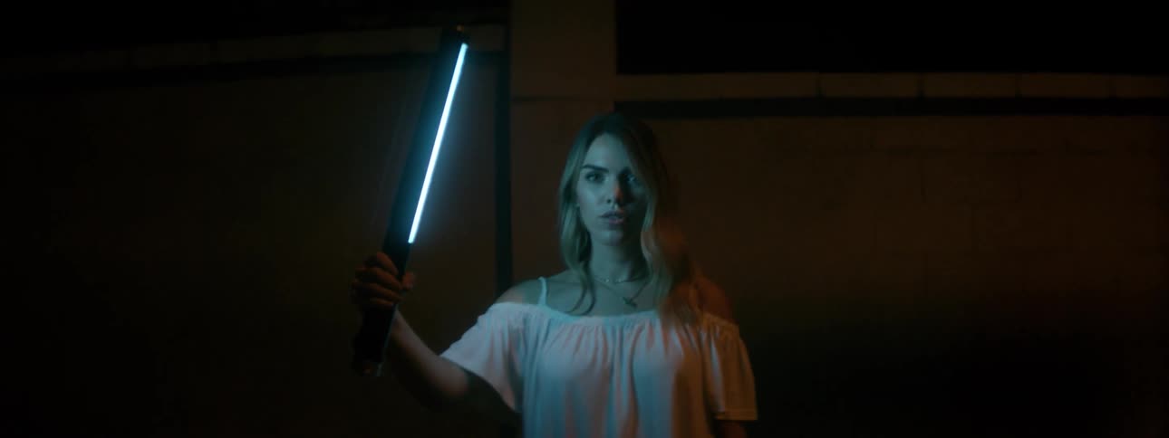 A woman lifts a glowing light outside at night