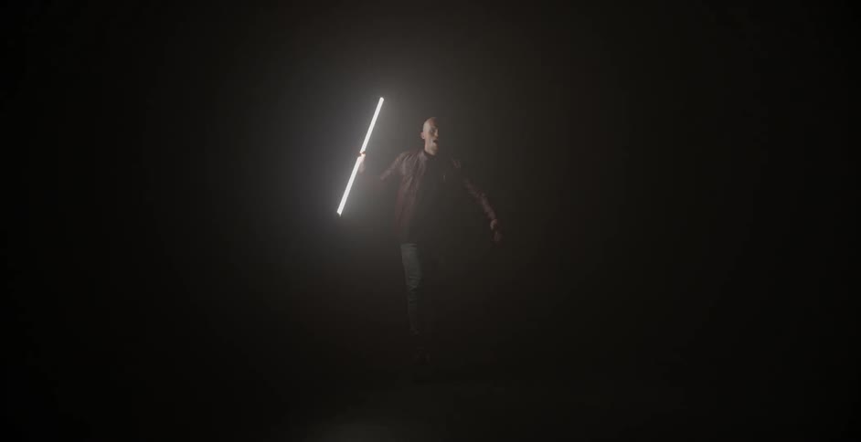 A man dances in a dark room with a large light