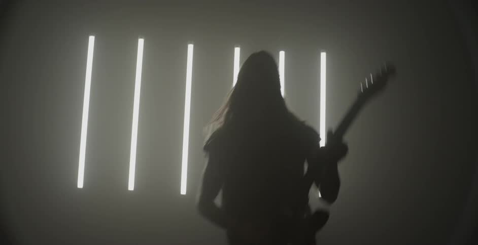 Man plays guitar in front of bright lights