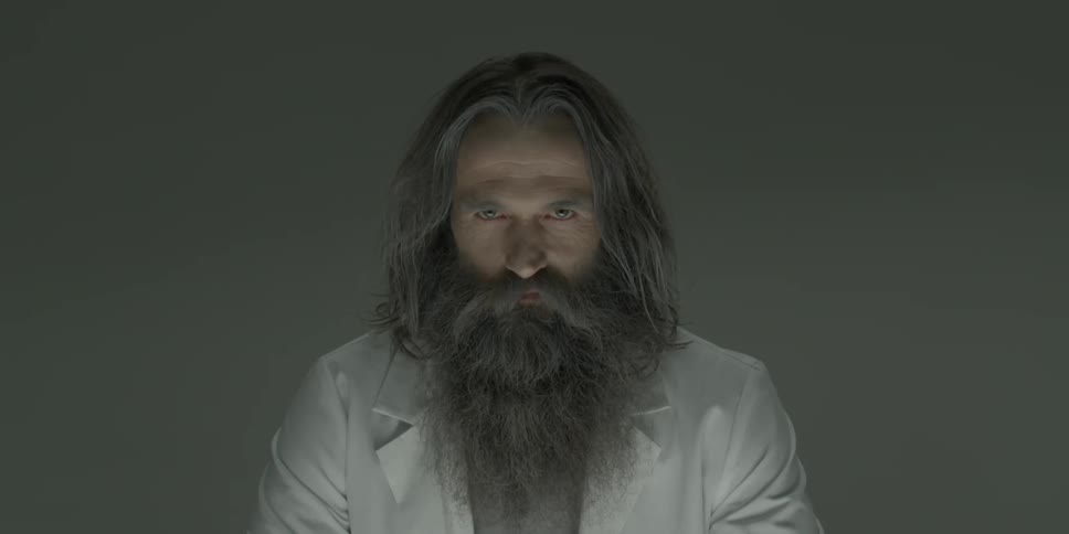 A bearded man stares intently