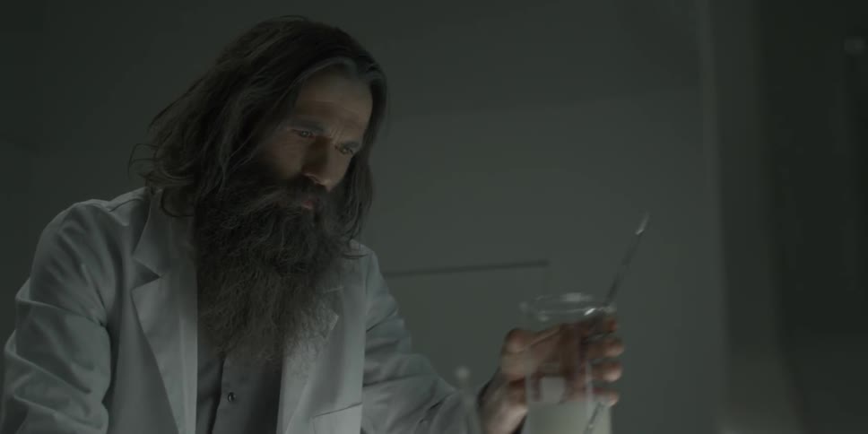 Man in lab coat lifts a beaker
