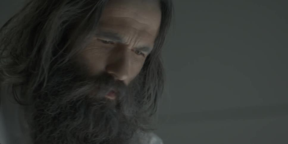 A bearded man stares intently