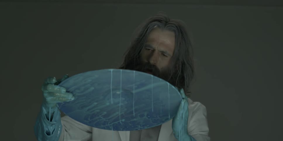 A man picks up a cymbal drum dipped in blue paint