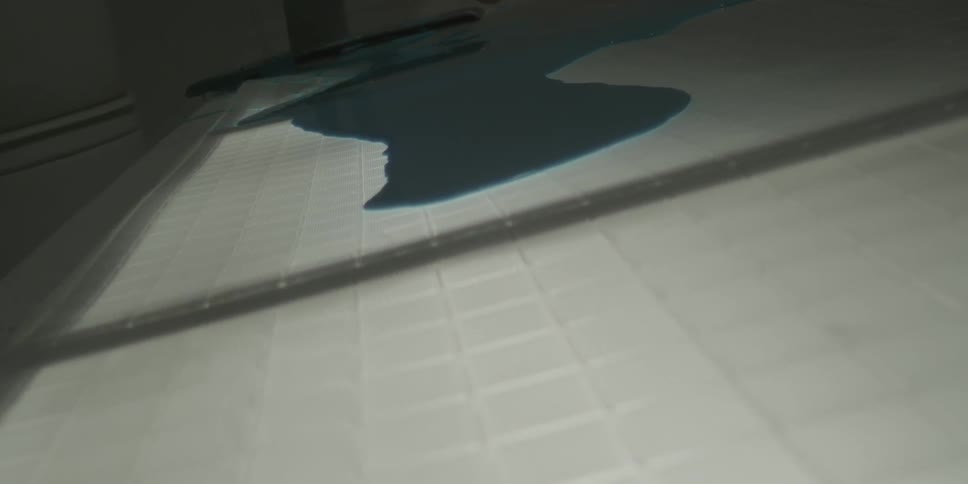 Dark liquid spreads out over a white surface
