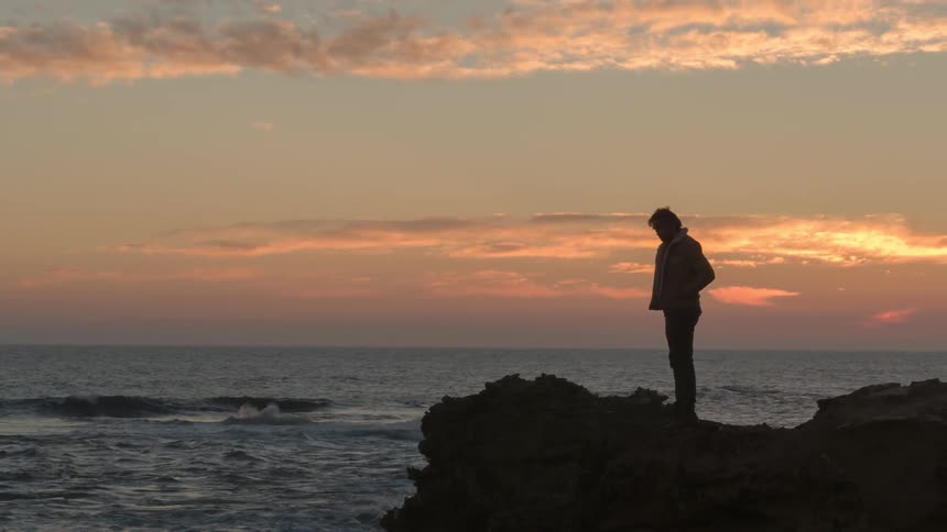 A man stands and looks out onto the water