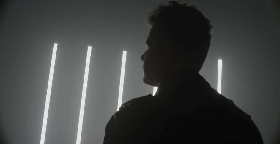A bassist plays and dances in a dim room