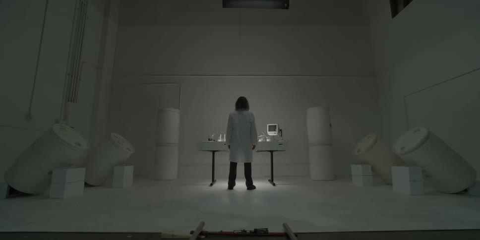 A man stands in a white room at a table with lab equipment