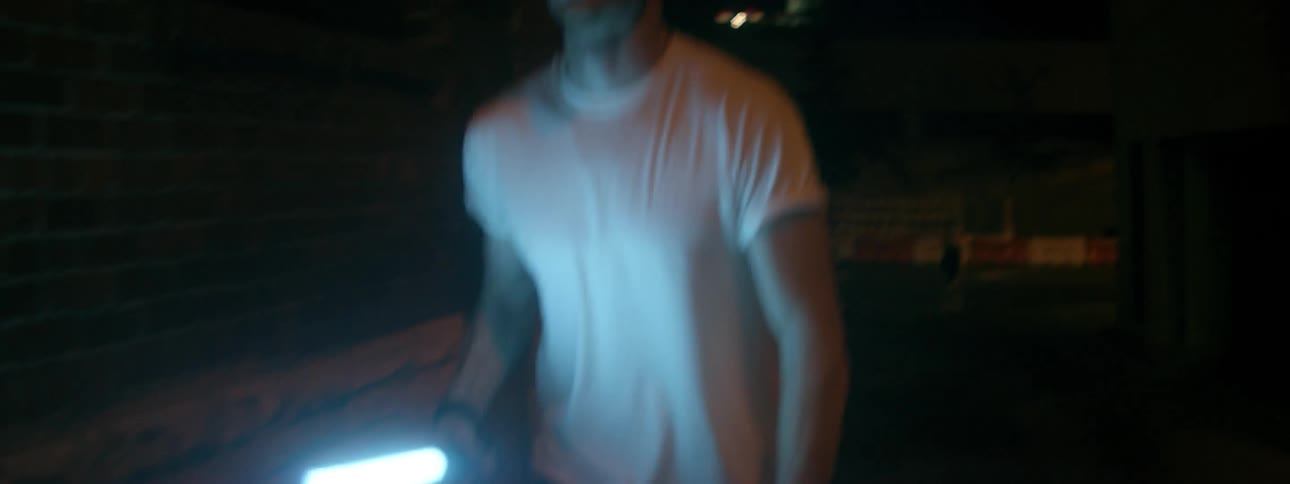 A man walks outside with a bright flashlight at night