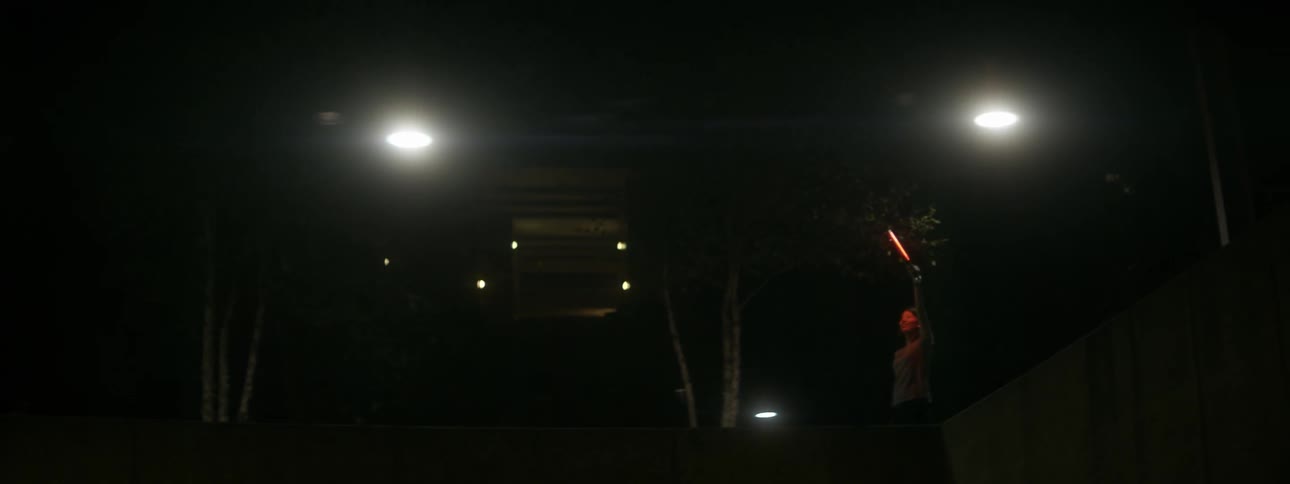 Person holds up a light next to a concrete pool at night