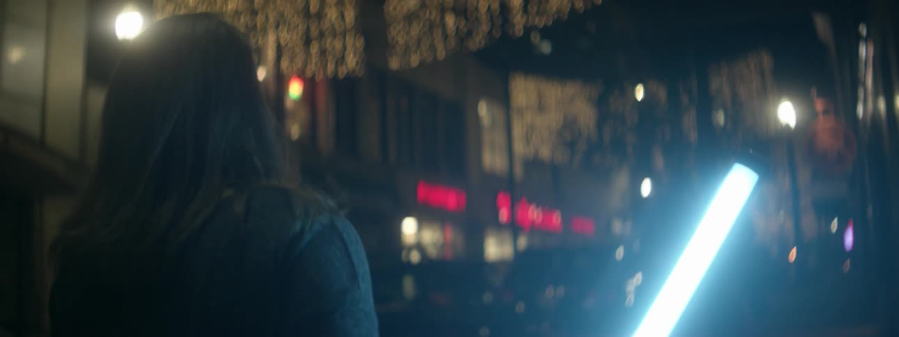 A woman walks outside at night with a bright flashlight