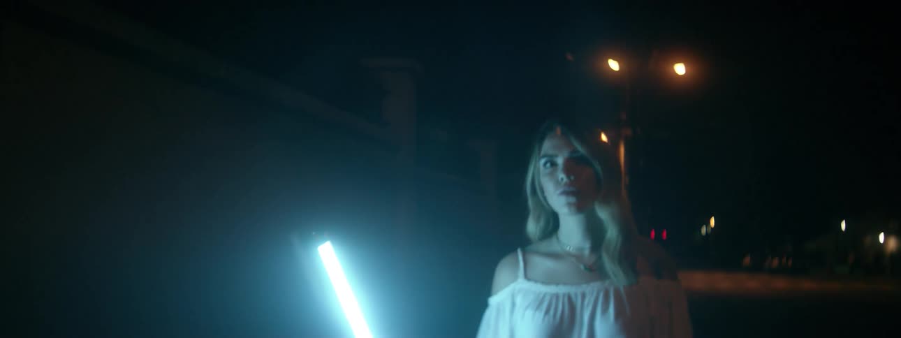 A woman is carrying a light stick as she walks outside at night